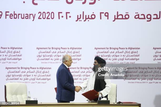 Special Representative for Afghanistan Reconciliation Zalmay Khalilzad and Taliban co-founder Mullah Abdul Ghani Baradar shake hands after signing...