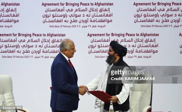 Special Representative for Afghanistan Reconciliation Zalmay Khalilzad and Taliban co-founder Mullah Abdul Ghani Baradar shake hands after signing a...
