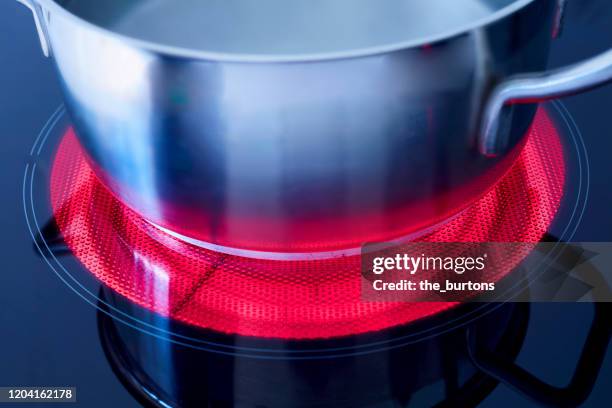 high angle view of a pot with boiling water on a heated ceramic stove top - keramische plaat stockfoto's en -beelden