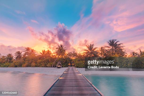 beautiful sunset beach scene. colorful sky and clouds view with calm sea and relaxing tropical mood - idyllic beach stock pictures, royalty-free photos & images