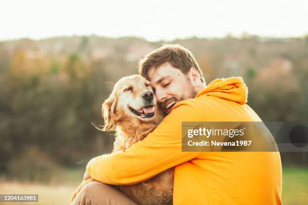 guy y su perro, golden retriever, naturaleza - cuddling animals fotografías e imágenes de stock