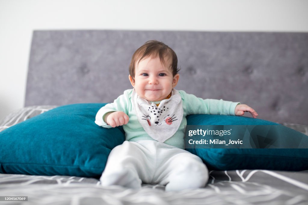 Newborn baby girl sitting with support pillows