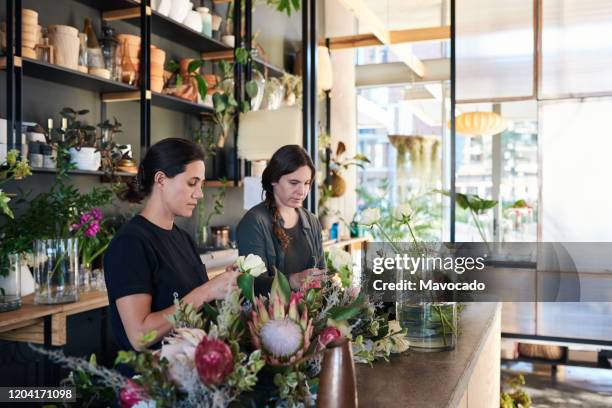 florists making floral arrangements in their flower shop - arranjo de flores imagens e fotografias de stock