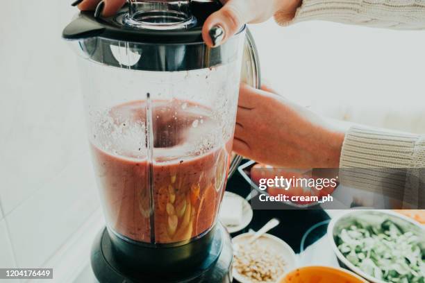 frau macht gesunden smoothie in der küche - avocado smoothie stock-fotos und bilder