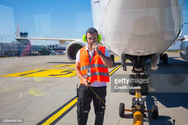 bodencrew schleppt flugzeug zur landebahn zum abflug - airport ground crew uniform stock-fotos und bilder