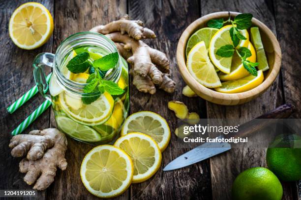 citroen en gember toegediend water op rustieke houten lijst - limonade stockfoto's en -beelden