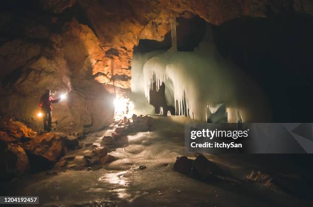 person zündet die eisige höhle an - grotte stock-fotos und bilder