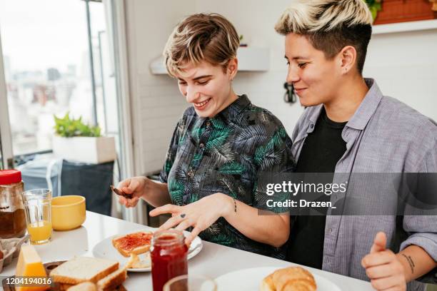 latin lesbians having breakfast at home - strawberry jam and butter - making a sandwich stock pictures, royalty-free photos & images