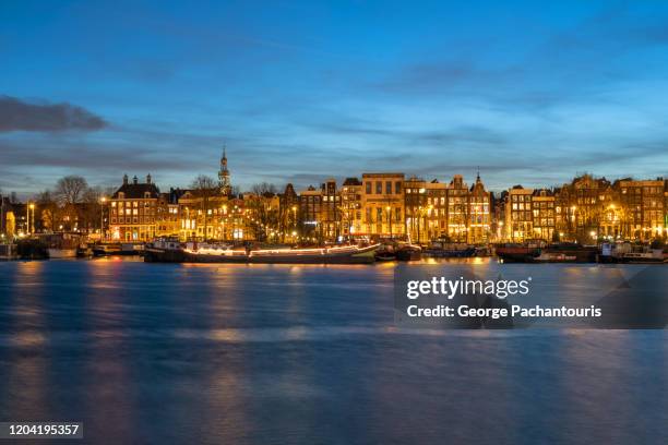 row of houses in amsterdam at dusk - amsterdam skyline stockfoto's en -beelden