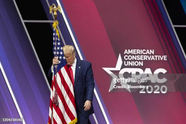 President Donald Trump hugs the American flag during the Conservative Political Action Conference in National Harbor, Maryland, U.S., on Saturday,...