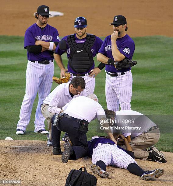 Pitcher Juan Nicasio of the Colorado Rockies is attended to by medical staff on the mound after being hit in the face by a ball while pitching...