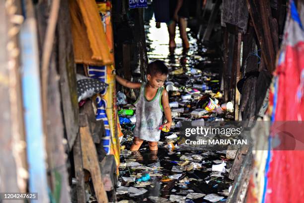 This photo taken on September 29, 2019 shows a child wading through the trash filled and polluted waters of a river beside their home in Manila.