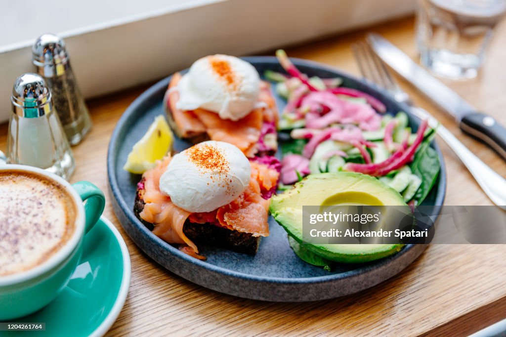 Poached eggs with salmon and avocado on the plate, side view