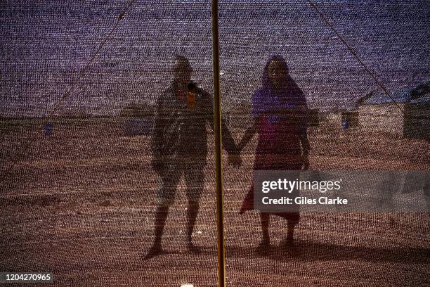 Tillaberi Refugee Settlement, Niger. December 13, 2019. A married refugee couple from Darfur stand on the scorched ground outside their shelter in...