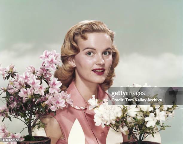 young woman standing beside flowers, portrait - archival woman stock pictures, royalty-free photos & images