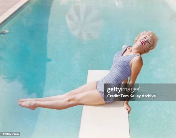 joven mujer sentada sobre trampolín, sonriendo, retrato - vintage woman diving fotografías e imágenes de stock