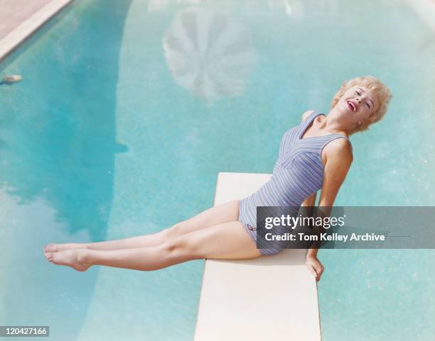 joven mujer sentada sobre trampolín, sonriendo, retrato - de archivo fotografías e imágenes de stock