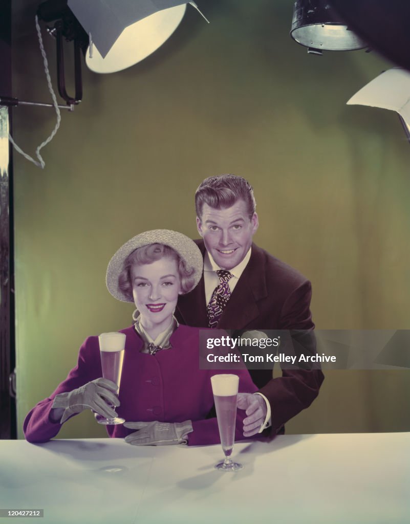 Casal segurando copos de cerveja, sorridente, retrato