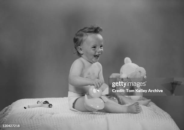 baby sitting on bed, playing with toys - 1950s bedroom stock pictures, royalty-free photos & images