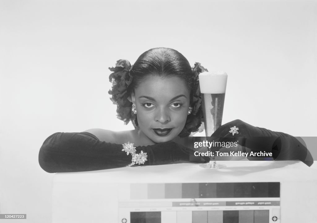 Young woman holding beer glass, smiling, portrait