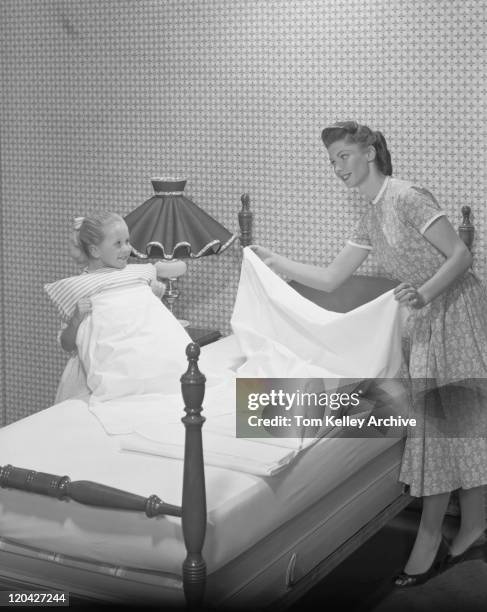 mother and daughter making bed together, smiling - 1950s bedroom stock pictures, royalty-free photos & images