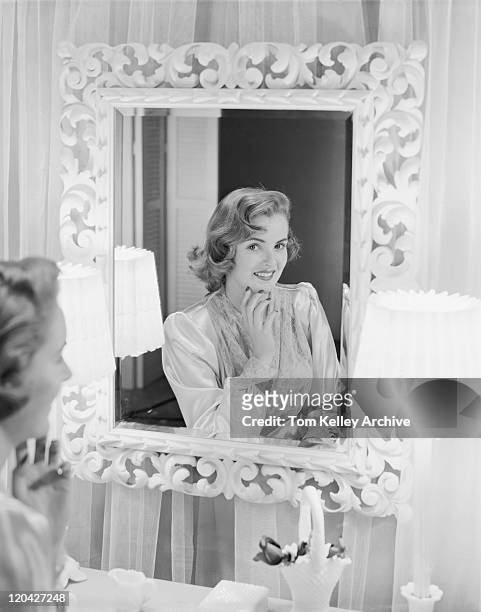 young woman looking in mirror, smiling - 1952 stock pictures, royalty-free photos & images