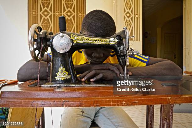 Boy from Nigeria who was formerly associated with armed groups in the Boko Haram controlled region of Nigeria behind his sewing machine at a...