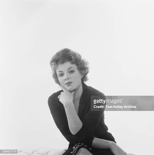 woman sitting against white background, portrait - 1950 1959 fotografías e imágenes de stock