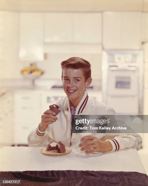 boy eating cake with glass of milk in kitchen, smiling - 1960 kitchen stock pictures, royalty-free photos & images