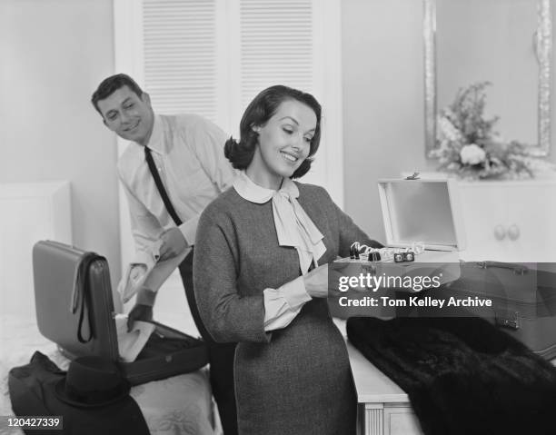 woman holding muscle toning device and man putting clothes in bag, smiling - 1961 stock pictures, royalty-free photos & images