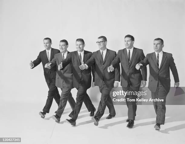 businessmen extending hand to shake, smiling - historisch stockfoto's en -beelden