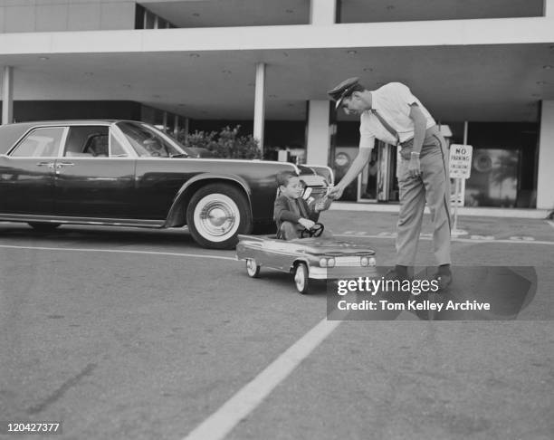 boy sitting in toy car giving paper to traffic police officer                                       - 1961 stock pictures, royalty-free photos & images