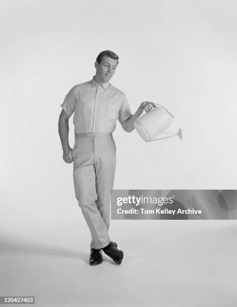 young man holding watering can, smiling - archival man stock pictures, royalty-free photos & images