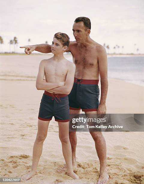 father and son standing on beach, father pointing  - archival 1960s stock pictures, royalty-free photos & images