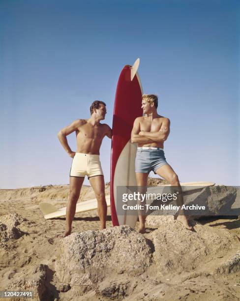 surfers mit surfbrett stehen am strand, die lächelnd - swimsuit stock-fotos und bilder
