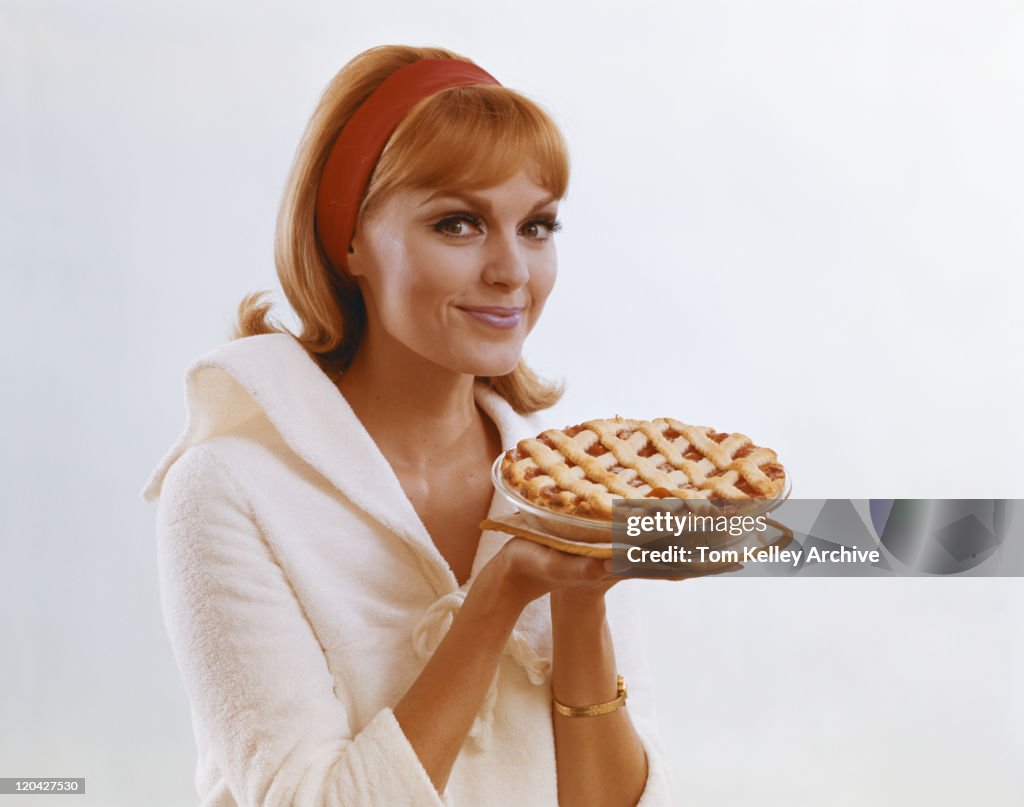 Young woman holding dessert pie against white background, portrait