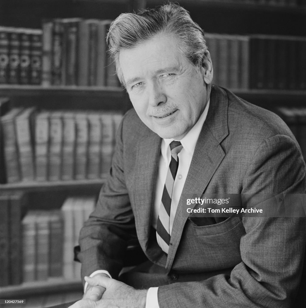 Senior man with bookshelf in background, portrait, close-up