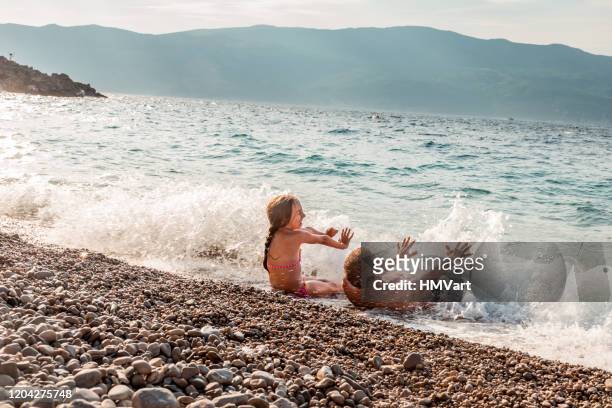 fröhliche vater und tochter im sommerurlaub genießen spritzen im meer und spielen mit wellen - croatia stock-fotos und bilder