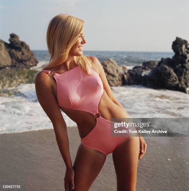 young woman in swimming costume standing on beach, smiling - 1969 stock pictures, royalty-free photos & images