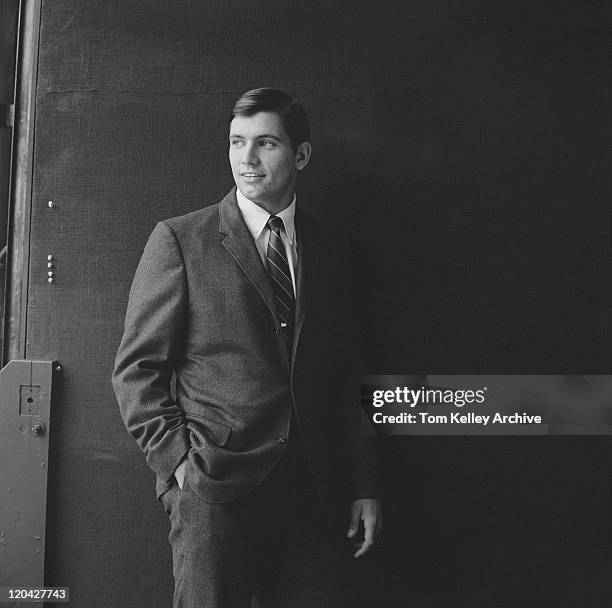 businessman standing against black background, smiling - sixties stockfoto's en -beelden