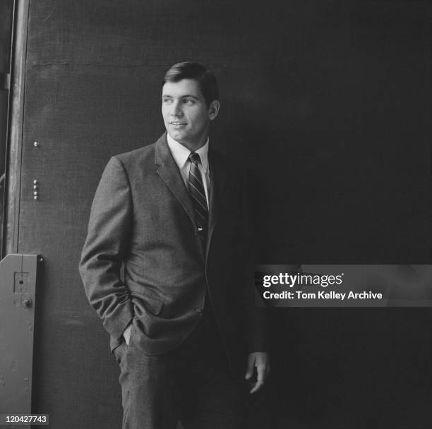 businessman standing against black background, smiling - swinging sixties stock pictures, royalty-free photos & images