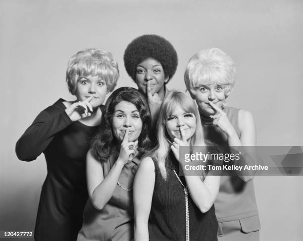 amigos com o dedo nos lábios em pé contra fundo cinza, sm - 1970 imagens e fotografias de stock