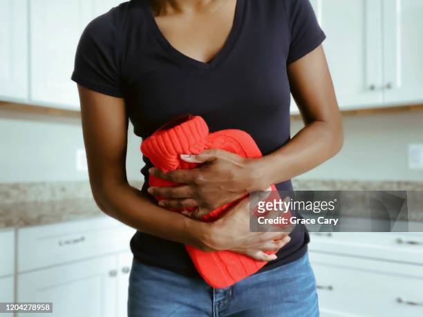 woman suffering from stomach pain uses hot water bottle - pm fotografías e imágenes de stock