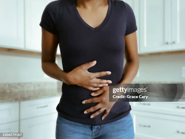 woman suffers stomach pains - femme main ventre photos et images de collection