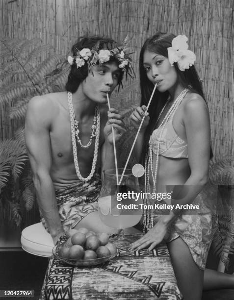 young couple in hawaiin costume drinking lemonade from same glass - 1975 vacations stock pictures, royalty-free photos & images