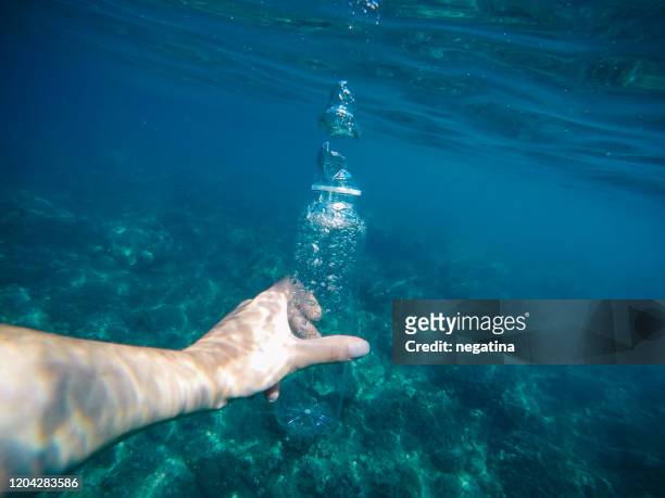 high angle of view underwater shot of the hand of young woman holding clear plastic bottle with big bubbles inside - big bottom woman stock-fotos und bilder