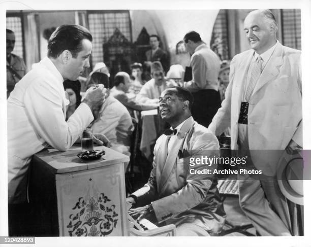 Humphrey Bogart leans on piano Dooley Wilson is playing in a scene from the film 'Casablanca', 1942.