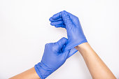 Doctor or nurse putting on blue nitrile surgical gloves, professional medical safety and hygiene for surgery and medical exam on white background