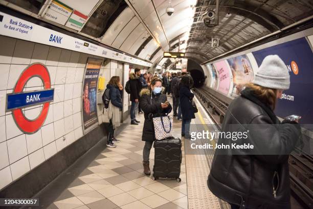 Woman wears a face mask while waiting for a tube train at Bank underground station on March 01, 2020 in London, England. There has been three more...