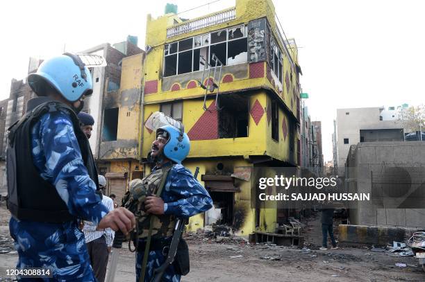 Police patrol a road as a man takes pictures of a partially burnt down building in a riot-affected area, in New Delhi on March 1 after violence broke...